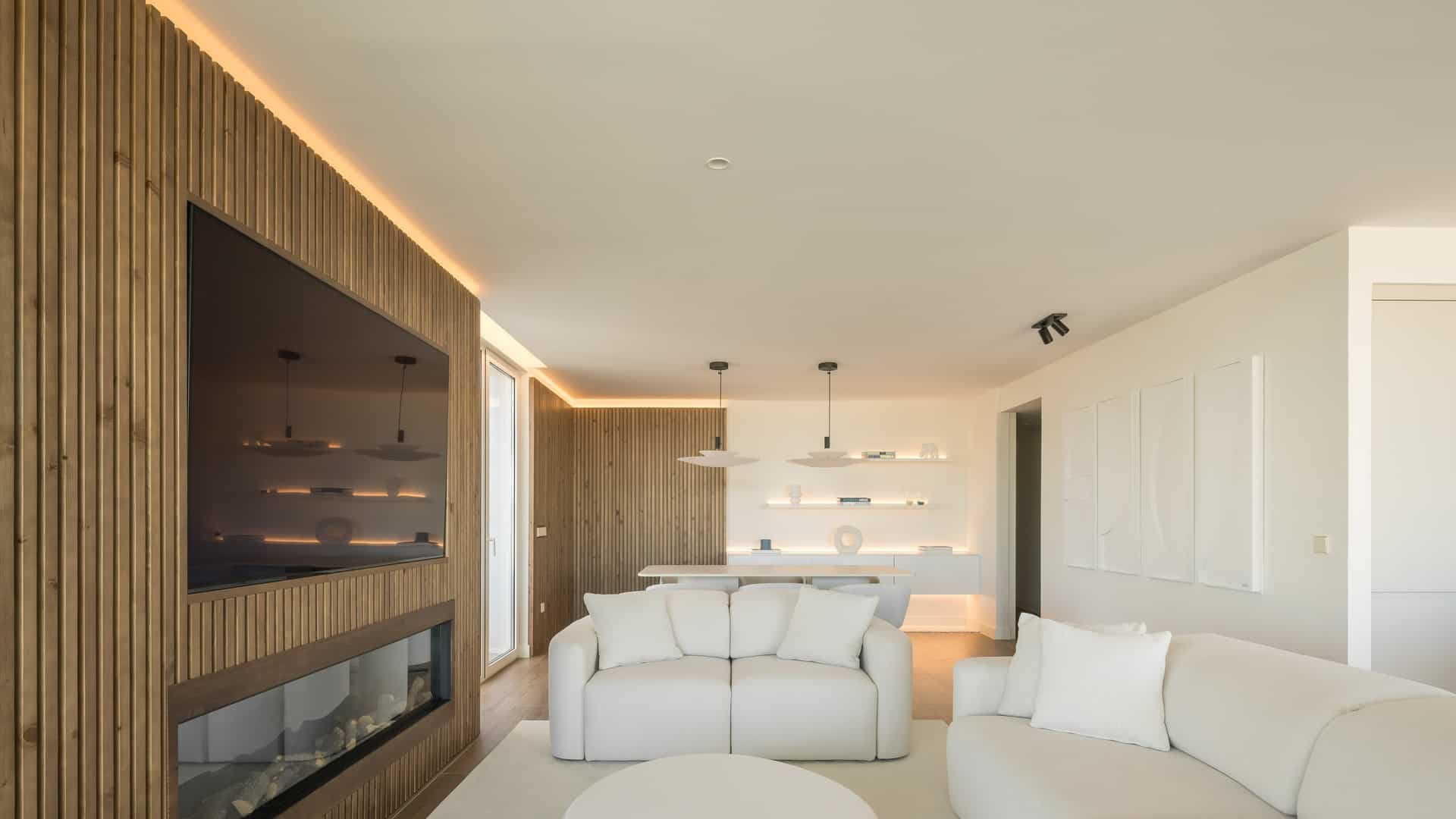 01.jpgSalón con panel de madera ranurada, cornisa de luz lineal LED y estanterías retroiluminadas, ático Edificio Ikon, JISO