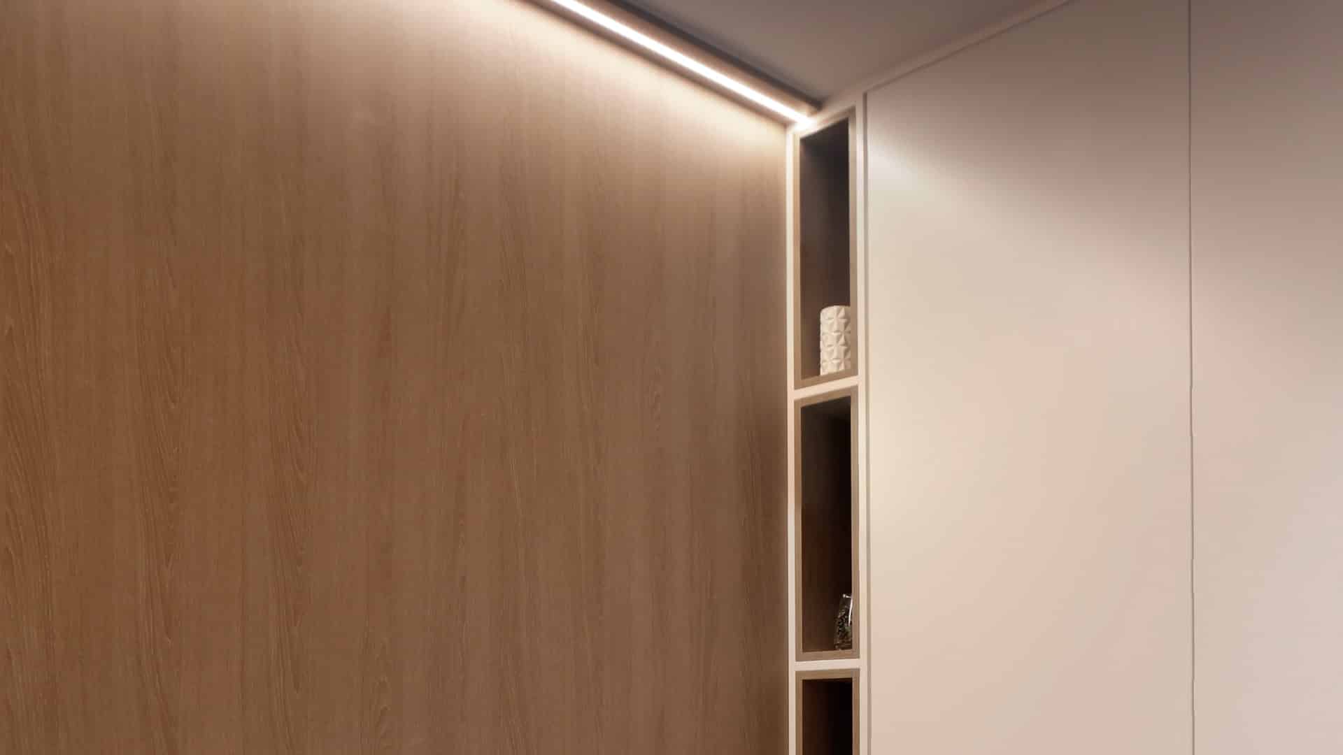 Panel de madera con cornisa de luz lineal LED y hornacinas iluminadas, despacho Jiso