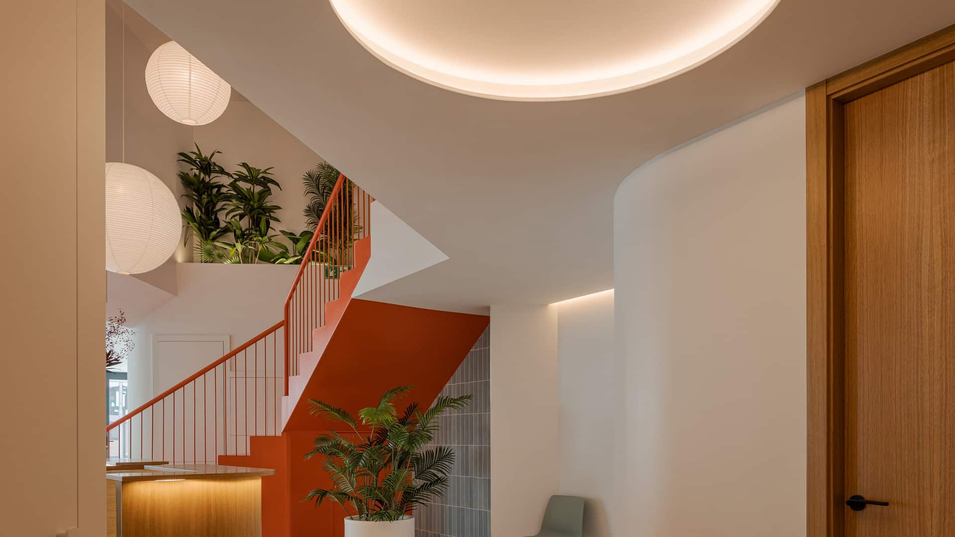 Plafón circular retroiluminado en techo sobre escalera de color, Clínica Novodent, iluminación Jiso