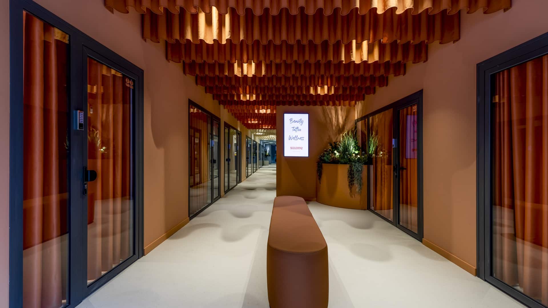 Techo de sistema lineal magnetic en tono cobre iluminando el pasillo de Suave Studio Valencia